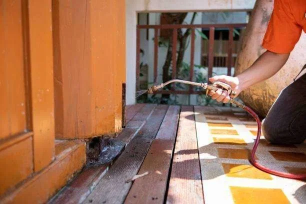 Pulverização para dedetização em pilar de madeira, com produto escorrendo no piso